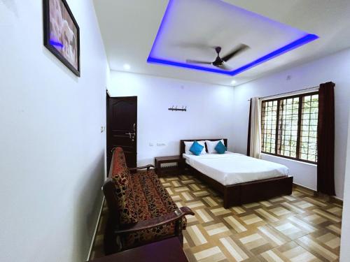 a bedroom with a bed and a couch and a blue ceiling at Deluxe Residency in Kalpetta