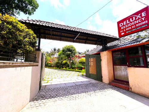 a building with a gate and a sign on it at Deluxe Residency in Kalpetta