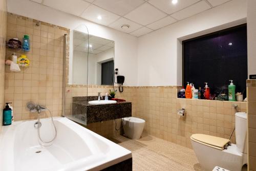 a bathroom with a tub and a toilet and a sink at Nirvana Home in Dubai