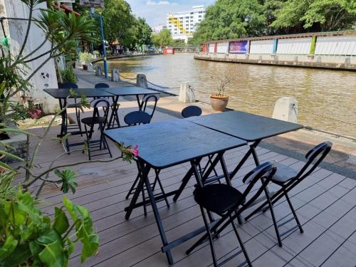 een rij tafels en stoelen naast een rivier bij V Space CAPSULE CAFE MELAKA in Melaka