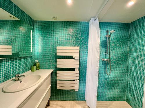 W wyłożonej niebieskimi kafelkami łazience znajduje się umywalka i prysznic. w obiekcie GITE LA VUE LOIRE Maison w mieście Saint-Denis-de lʼHôtel