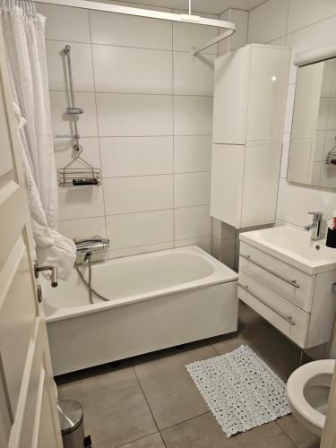 a white bathroom with a tub and a sink at Montana Guest House. in Lillestrøm