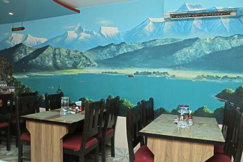 a restaurant with two tables and a mural of mountains at Hotel Readers Inn Pvt.Ltd in Kathmandu