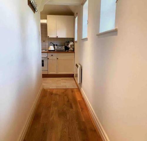 a small kitchen with white walls and wooden floors at A charming cottage in a beautiful setting. in Hungerford