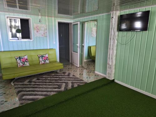 - un salon avec un canapé et un mur vert dans l'établissement Paille en queue, à Saint-Leu
