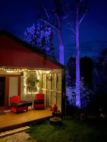 a house with lights on the deck at night at The Red Cottage in Wentworth Falls