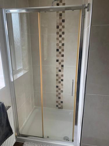 a shower with a glass door in a bathroom at Comfort Home in Wigan