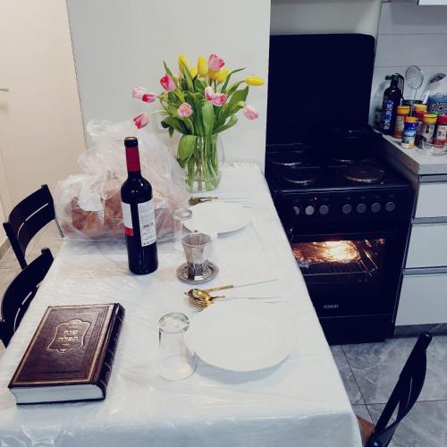 uma mesa com uma garrafa de vinho e um vaso de flores em ירושלים של זהב em Jerusalém