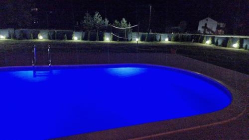 una gran piscina azul por la noche con luces en Vikendica Stjepanović, en Teslić