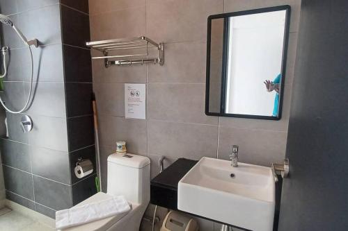 ein Badezimmer mit einem WC, einem Waschbecken und einem Spiegel in der Unterkunft Aesthetic 2BR @ Urban Suite (Infinite Pool & Gym) in Jelutong