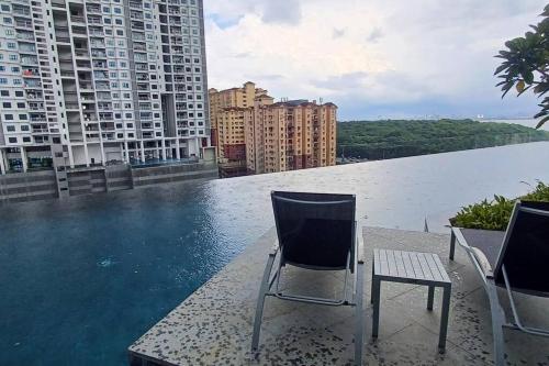 two chairs sitting on the edge of a swimming pool on a building at Aesthetic Urban Suite With Infinite Pool & Gym in Jelutong
