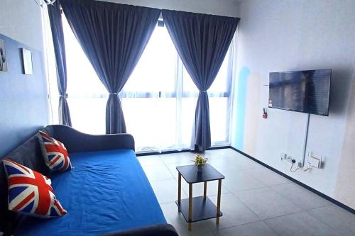 a living room with a blue couch and large windows at Aesthetic Urban Suite With Infinite Pool & Gym in Jelutong