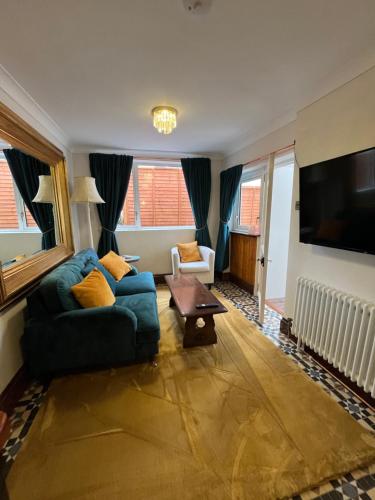 a living room with a blue couch and a tv at Captain's Nook, Luxurious Victorian Apartment with Four Poster Bed and Private Parking only 8 minutes walk to the Historic Harbour in Brixham