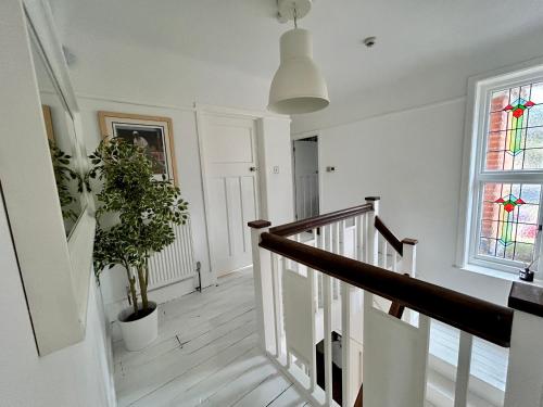 a white hallway with a staircase and a window at Palm - Bournemouth in Bournemouth
