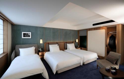 a hotel room with two beds and a chair at Hotel Collective in Naha