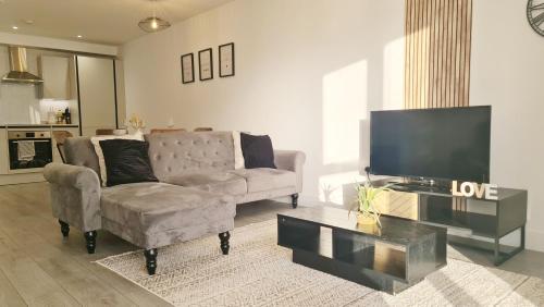 a living room with a couch and a flat screen tv at Premium CITY APARTMENT near Harry Potter Studio and Luton Airport in Hemel Hempstead