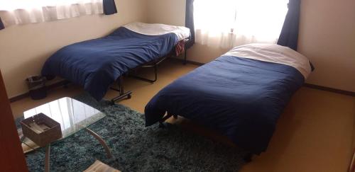 two twin beds in a room with a window at Guest House Koriyama in Koriyama