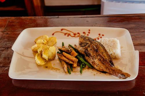 a plate of food with meat and potatoes on a table at Long Beach Resort, Nosy Be in Nosy Be