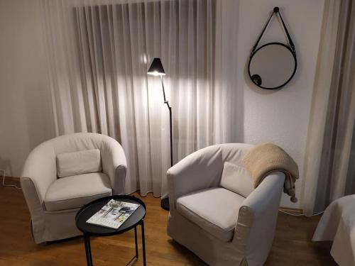 een kamer met 2 stoelen, een tafel en een lamp bij Ferienwohnung mit Bergblick in Frastanz