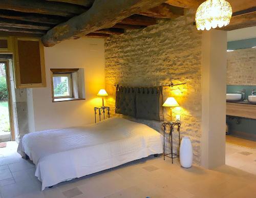 une chambre avec un lit blanc et un mur en pierre dans l'établissement NEW ! Gîte L'Écrin de Coeur - Village-Rivière-Canal Bourgogne, à Cry