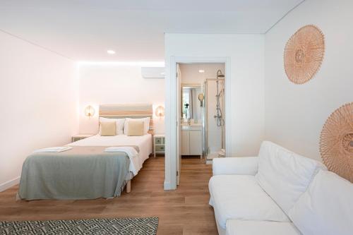 a white bedroom with a bed and a couch at Quinta Das Essências in Penafiel