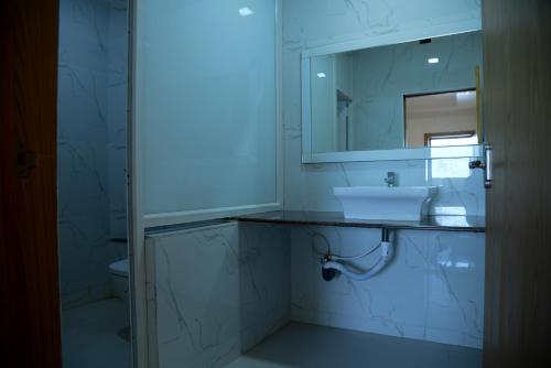 a white bathroom with a sink and a mirror at Hotel Tri Sea in Kanyakumari
