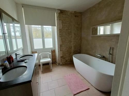 y baño con bañera, 2 lavabos y bañera. en Moulin de Bellicout, en Charmé