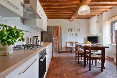 una cocina con armarios blancos y una mesa con sillas. en Agriturismo La Gioconda, en Vinci