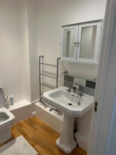 a white bathroom with a sink and a toilet at Lovely Two Bedroom Flat in Thamesmead