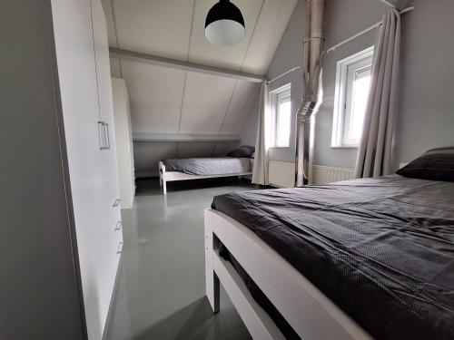 um quarto com uma cama e duas janelas em Vrijstaande vakantie woning em Wolphaartsdijk