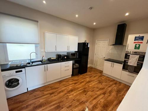 a kitchen with white cabinets and a washer at Victoria Apartments in Torquay