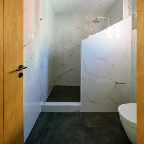 a bathroom with white marble walls and a toilet at Lotus Suites in Fira