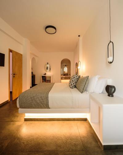 a bedroom with a large white bed and a table at Lotus Suites in Fira