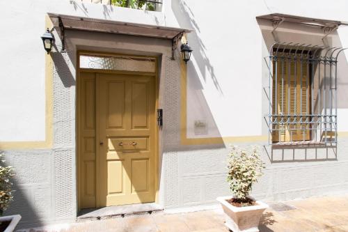 une porte jaune sur un bâtiment blanc avec une plante en pot dans l'établissement 17 flats and Roof Garden, à Athènes