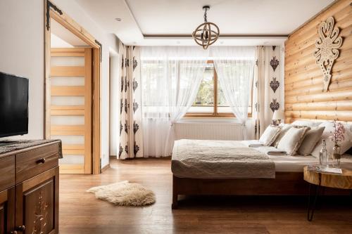 a bedroom with a bed and a tv and a window at Villa Odskocznia Apartamenty Zakopane in Zakopane