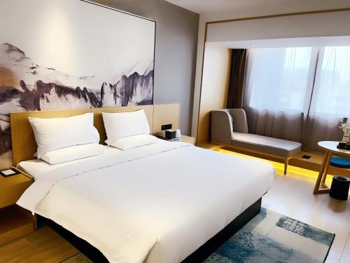 - une chambre avec un grand lit blanc et une chaise dans l'établissement Tuke China Hotel Shanghai Hongqiao Airport, à Shanghai