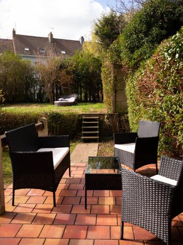 a patio with chairs and tables on a brick patio at Spa , jardin 250m2 et appartement cosy de 60 m2 au centre in Boulogne-sur-Mer