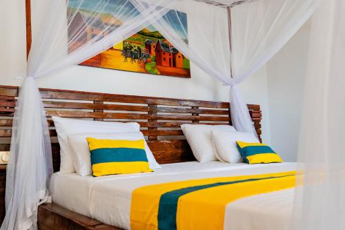 um quarto com uma cama com almofadas amarelas e azuis em Long Beach Resort, Nosy Be em Nosy Be