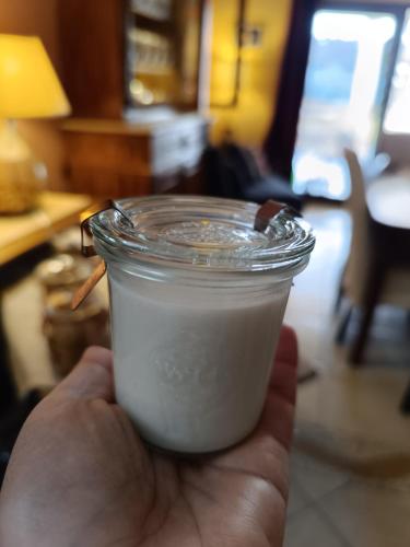 a hand holding a glass jar of milk at Il Sentiero B&Bìo in SantʼAntìoco