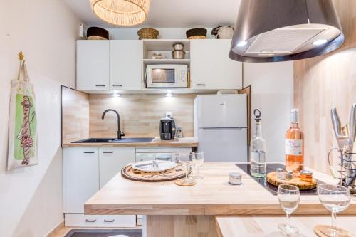 a kitchen with white cabinets and a counter with wine glasses at Maison - Residence avec piscine in Calvisson
