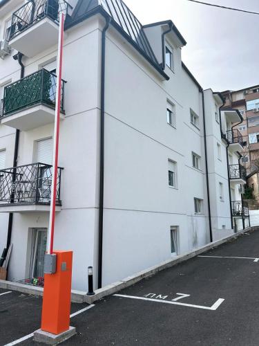 a white building with an orange pole in a parking lot at Apartman Comfort Beograd in Belgrade