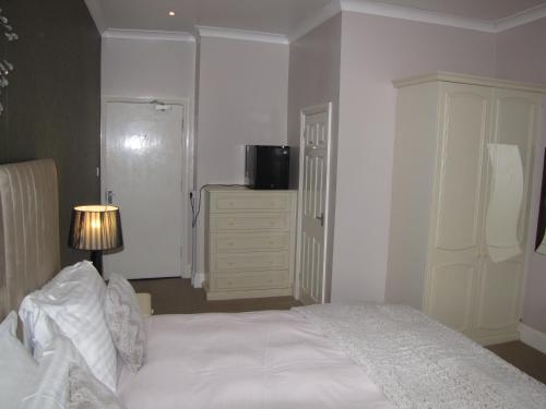 a bedroom with a large white bed and a dresser at Ashmira Guest House in Weymouth