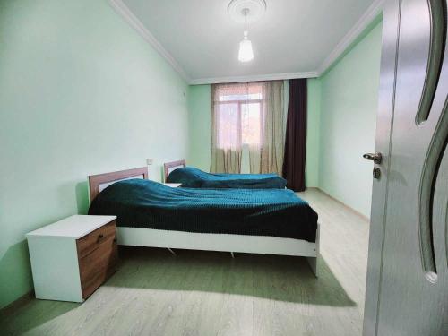 um quarto com uma cama com lençóis azuis e uma janela em 53 jincharadze street em Batumi