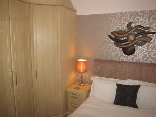 a bedroom with a bed and a lamp on a night stand at Ashmira Guest House in Weymouth