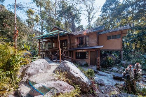 a house in the woods with rocks in front of it at ธารทอง ลอดจ์ Tharnthong Lodge in Ban Pang Champi