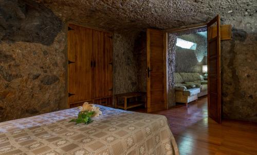 um quarto com uma cama com um vaso de flores em Casa Cueva Las Margaritas em Artenara