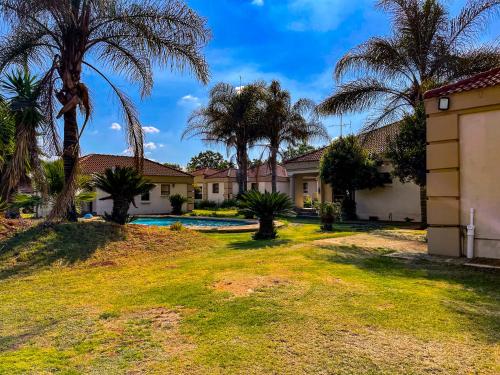 a house with palm trees and a swimming pool at Bobisemo Luxury Pretoria East Apartment in Tierpoort