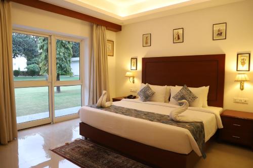 a bedroom with a large bed and a large window at Hotel Chandela Khajuraho in Khajurāho