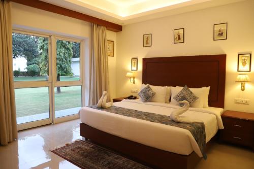 een slaapkamer met een groot bed en een groot raam bij Hotel Chandela Khajuraho in Khajurāho