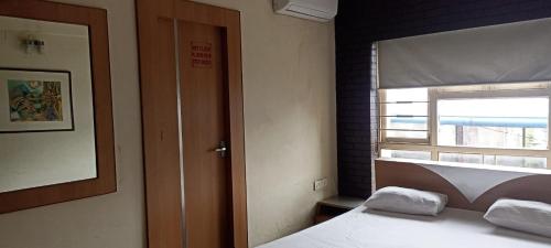 een slaapkamer met een bed en een raam met een raampje bij Ballygunge Guest House in Calcutta